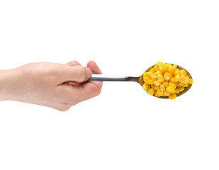 Canned corn on a white background. A hand holds an iron spoon of canned corn close up.