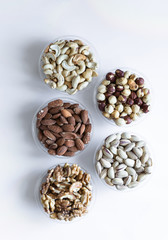 Healthy food. Nuts mix assortment on white grey table top view. Collection of different legumes for background image close up nuts, pistachios, almond, cashew nuts, peanut, walnut. image