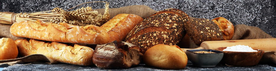 Assortment of baked bread and bread rolls on rustic grey bakery table background