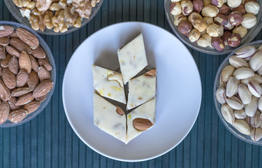 Oriental dessert halva with pistachio, almond, cashew nuts, peanut, walnut  on a  plate. Image. Healthy food. Nuts mix assortment. closeup of sweets  Isolated on background. Collection of different 
