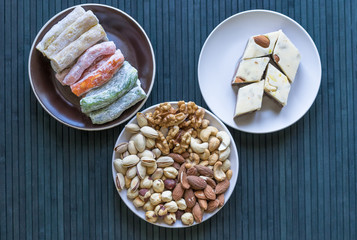 Oriental dessert halva with pistachio, almond, cashew nuts, peanut, walnut  on a  plate. Image. Healthy food. Nuts mix assortment. sweets, Turkish Delight. Isolated  background.. Eastern delicacy