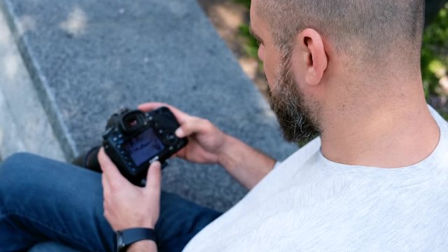 Bearded photographer looks at photos on his DSLR camera