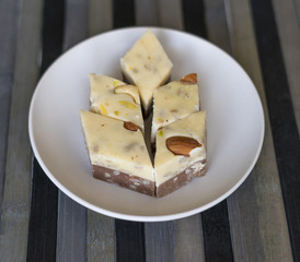 Oriental dessert halva with pistachio, almond, cashew nuts, peanut, walnut  on a  plate. Image. Healthy food. closeup of sweets  Machane Yehuda Market, Turkish Delight. Isolated on white background