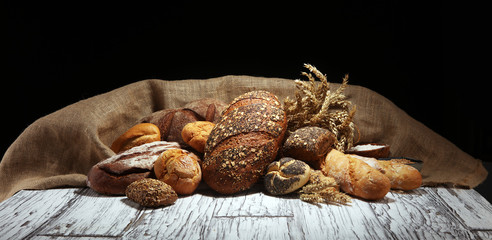Assortment of baked bread and bread rolls on rustic white bakery table background