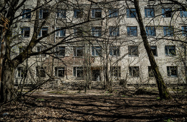 Fototapeta na wymiar Street of the abandoned ghost town Pripyat. Overgrown trees and collapsing houses in the exclusion zone of the Chernobyl nuclear disaster