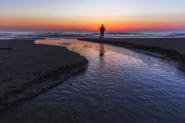 Fototapeta premium A young guy meets the sunrise by the sea