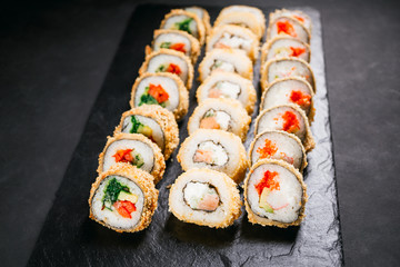 Tempura maki. Japanese sushi rolls set on black slate. Japanese traditional fusion food style, restaurant menu, degustation, buffet