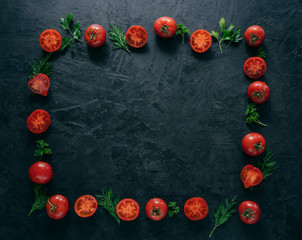Flat lay of red ripe tomatoes lies in form of frame on dark background with green parsley and dill. Healthy vegeterian dish. Horizontal shot. Copy space for text