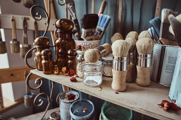 Glass jars, different brushes and other tools on a shelf at art studio.