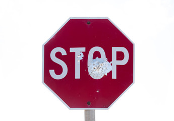 Red road stop sign full of bullet holes