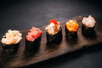 Set of five different gunkan maki sushi rolls on wooden plate. Degustation, gastronomy, seafood Japanese restaurant menu concept, banquet chef cuisine