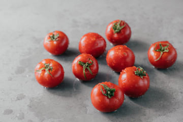 Close up shot of red tasty heirloom tomatoes with green leaves and water droplets harvested from garden isolated over grey background.