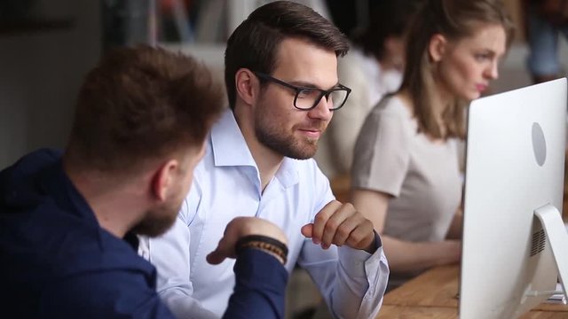Two male colleagues cooperating in office talking working together