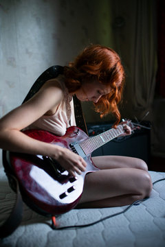 girl playing guitar sitting on her lap