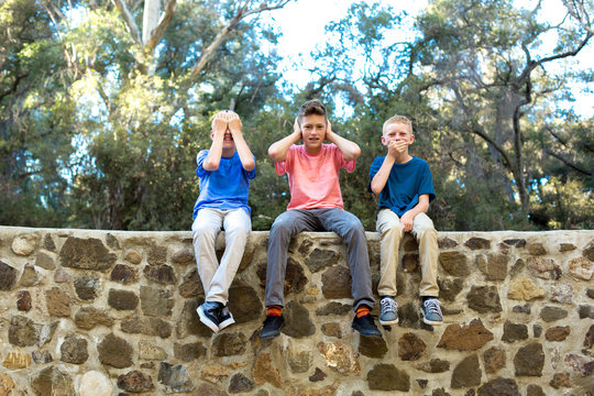 Three boys sitting on a wall see no evil, hear no evil, speak no evil