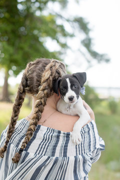 the back of a girl with pick tails holing a dog with sad eyes in Glost