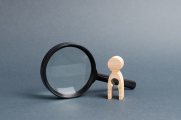 A wooden figure with a baby-shaped void stands near a magnifying glass. concept of infertility and women and the inability to have children. Abbort, the loss of a child. Treatment and Prevention