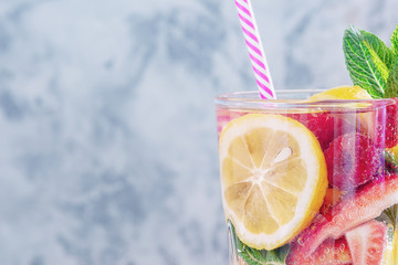 Glass of lemonade with a straw closeup. Fresh healthy drink from lemon, strawberry and raspberry. Photo with space for text, copy space.