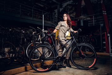 Diligent attractive woman is trying fixed bicycle at busy workshop.