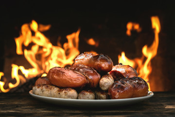 Grilled sausages on a burning fire background on the kitchen table.