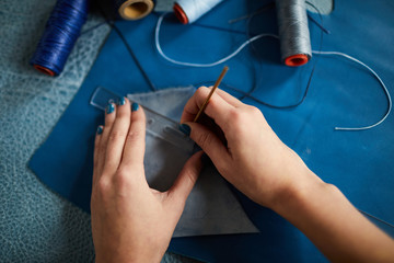 Top view closeup of female hands sewing leather clothes in dressmaking shop, copy space