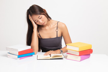 Exhausted Young Asian woman read a book with books on table.