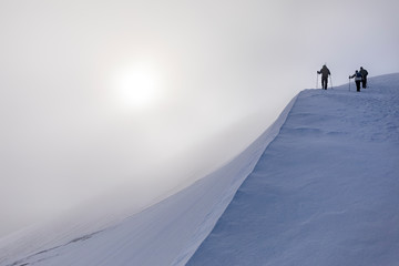 Hikers at top of steep snowy slope