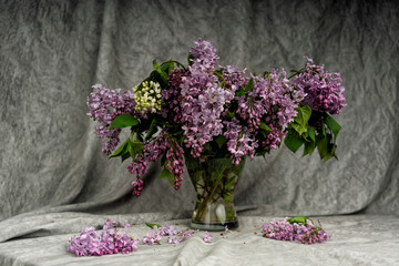 Bouquet of lilac in a glass vase. A bouquet of lilac on a white tablecloth table.