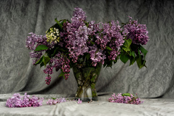 Bouquet of lilac in a glass vase. A bouquet of lilac on a white tablecloth table.