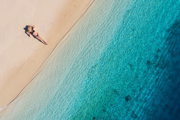 Aerial view of a girl on the beach on Bali, Indonesia. Vacation and adventure. Beach and turquoise water. Top view from drone at beach, azure sea and relax girl. Travel and relax - image