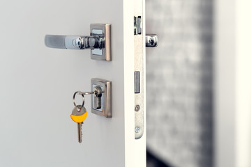 Open white door at home. Handle key close up.