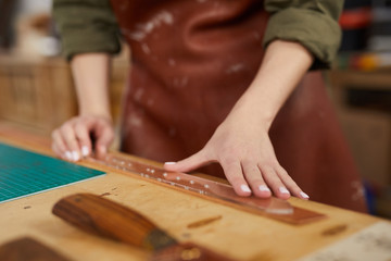 Close up of unrecognizable woman doing leather craft in workshop, copy space