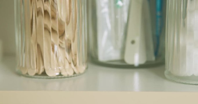 A small vial of measles MMR vaccine and syringe being removed from a shelf by plastic latex gloved hands.