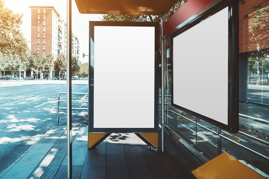 Mockup of two empty poster placeholders inside of an urban bus stop; template of blank white banners indoors of a station of public transport; empty outdoor billboards mockups in city settings