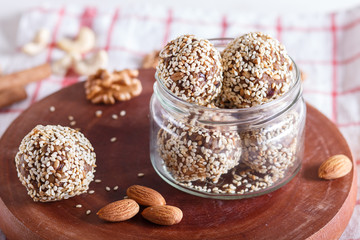 Energy balls cakes with almonds, sesame, cashew, walnuts, dates and germinated wheat in glass jar, side view, close up.