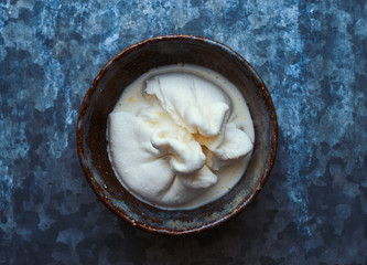Fresh white Italian burrata mozzarella cheese in a bowl top view space for text 