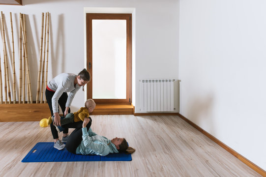 Fitness instructor helping mother with push ups