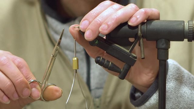 Man making trout flies. Fly tying equipment and material for fly fishing preparation .