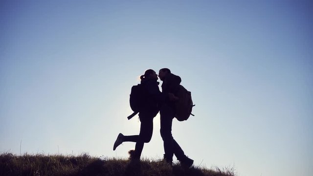 happy family teamwork friendship love romance business travel concept. couple of tourists man and woman with backpacks silhouette kissing on top of a mountain near a small dog. hikers couple kiss and