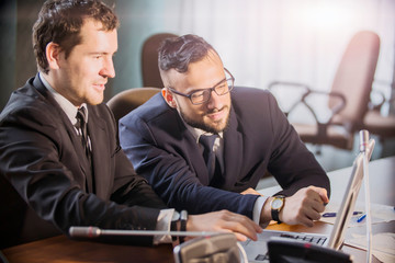  Image of two young businessmen discussing document in touchpad at   meeting