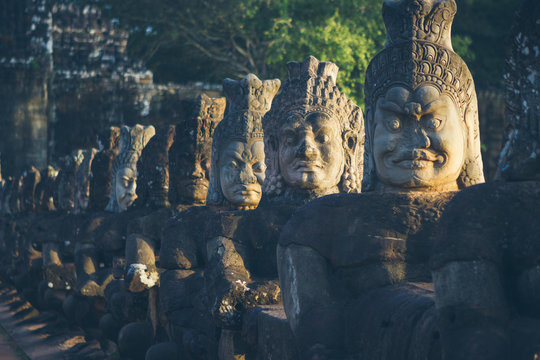 Row of weathered stone statues located near old oriental temple on sunny day