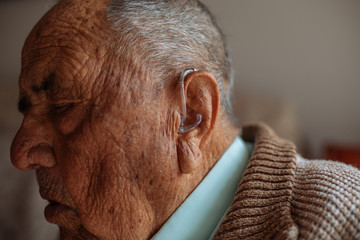 Detail of a hearing aid in an old man