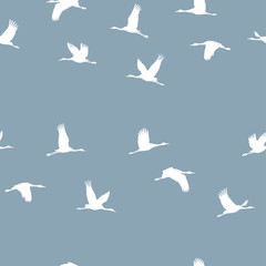 Seamless pattern with a flock of white cranes on a blue background. Vector.