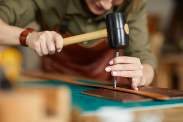 Close up of woman artisan making leather belt in leatherworking shop , copy space