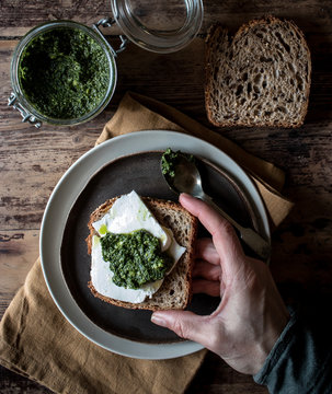 From above plate with tasty rye toast with cheese and fresh pesto placed on timber tabletop