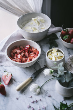 Various fresh ingredients for tasty strawberry pastry placed on marble tabletop in kitchen