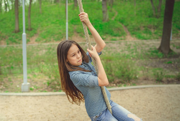 Smiling girl riding around on rope Charming cheerful brunette girl with eyes closed riding around on rope on playground in park