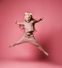 Little red-haired girl in cute pajamas and hair bandages jumping