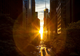 Rays of sunlight shining between the skyline buildings along 42nd Street in Midtown Manhattan, New York City