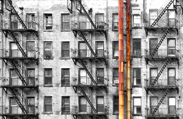 Black and white apartment building with colorful old rusted metal pipes in New York City - obrazy, fototapety, plakaty